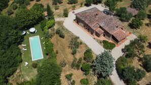 Vista aerea di una struttura con piscina, un edificio grande con tetto in tegole e vegetazione circostante.