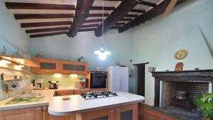 Cucina con mobili in legno, piano cottura a gas, frigorifero e forno integrato.