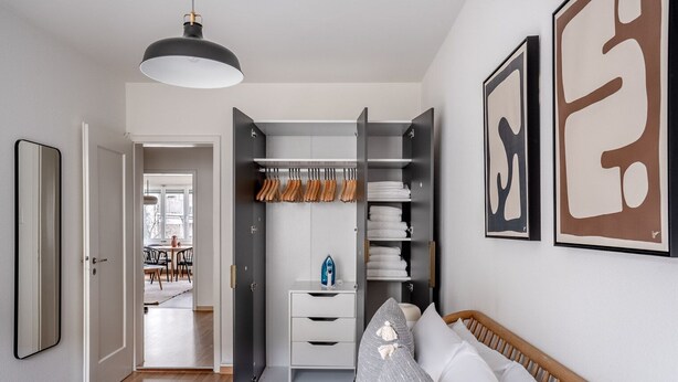 A bedroom with a bed, a wardrobe, and a bedside table. - Tasteful Iselin 2BR w/ Storage, steps to Central Market, by Blueground (Basel)