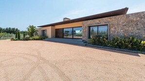 A modern house with a stone facade, large windows, and a gravel driveway. - Son Rius (Muro)