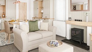 Un salon chaleureux avec un canapé, un pouf et une cheminée.