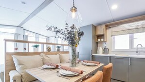 Une cuisine moderne avec un coin repas, des meubles en bois et un luminaire suspendu.