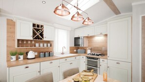 Une cuisine moderne avec des meubles blancs, un plan de travail en bois et des luminaires suspendus en cuivre.