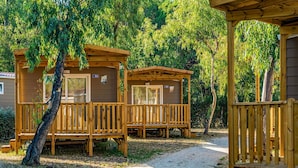 A wooden cabin with a porch and a window, surrounded by trees and a gravel path. - Nice apartment in villa for 4 people with A/C, WIFI, pool, TV, terrace and pets allowed (Rome)