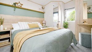 A bedroom with a bed, bedside tables, a nightstand, a window, and a mirror.