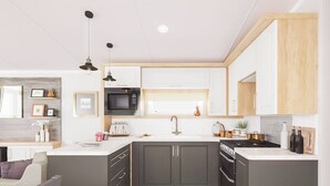 A modern kitchen with dark cabinets, a white countertop, a built-in microwave, and a gas stove.
