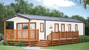 A single-story mobile home with a porch, a small deck, and a front entrance.