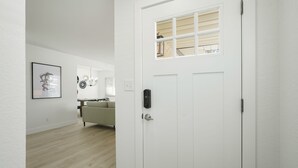 A white door with a peephole and a window above it. - DenverStays: 5BR Stylish and Modern Home w/Garage, great for pets and families! (Arvada)