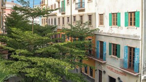 A row of buildings with balconies and green shutters, a street in front, and a sign for 'NAU BAO COFFEE & RESTAURANT'. - Cybele Sunset Hotel Phu Quoc (Phu Quoc)