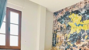 A bedroom with a large bed, a view of the sea through a window, and a colorful abstract painting on the wall. - Cybele Sunset Hotel Phu Quoc (Phu Quoc)