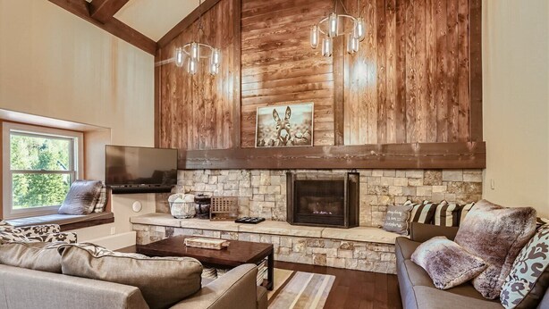 A cozy living room with a stone fireplace, wooden walls, and modern furniture.