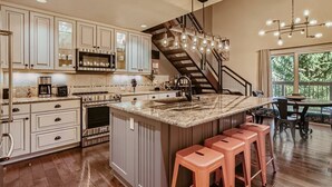 A modern kitchen with a central island, stainless steel appliances, and a staircase leading to a balcony.