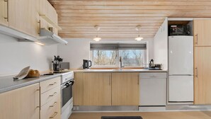 A modern kitchen with wooden cabinets, a built-in oven, a refrigerator, and a window providing natural light.