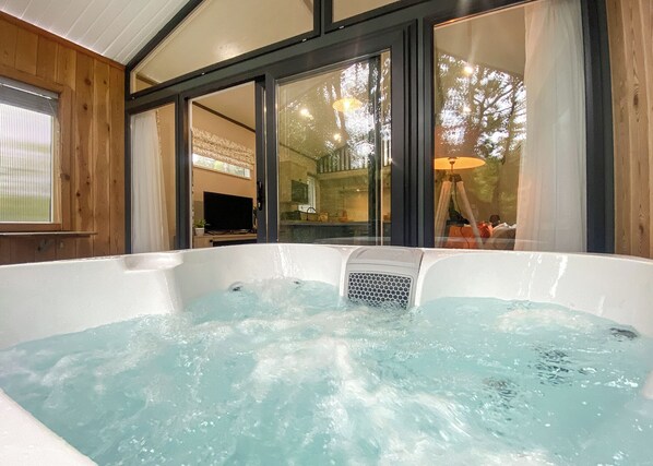 Un jacuzzi con vista a una habitación que tiene un televisor y una lámpara.