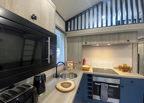 Une cuisine moderne équipée d’un four à micro-ondes, d’un grille-pain, d’un évier et d’un four encastrés.
