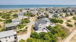 A residential area with houses, a swimming pool, and a beach in the background. - Shiner Shore Shack: 1200 Ft to Beach Access, Pool, Hot Tub (Corolla)