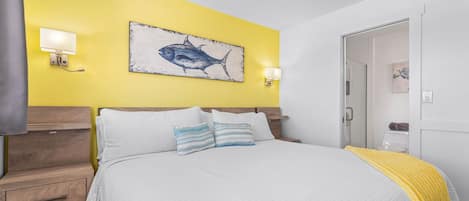 A bedroom with a bed, bedside tables, a wall-mounted light, and a fish painting.