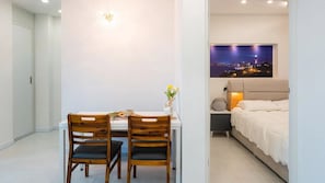 A modern hotel room with a bed, bedside table, and a night view poster.