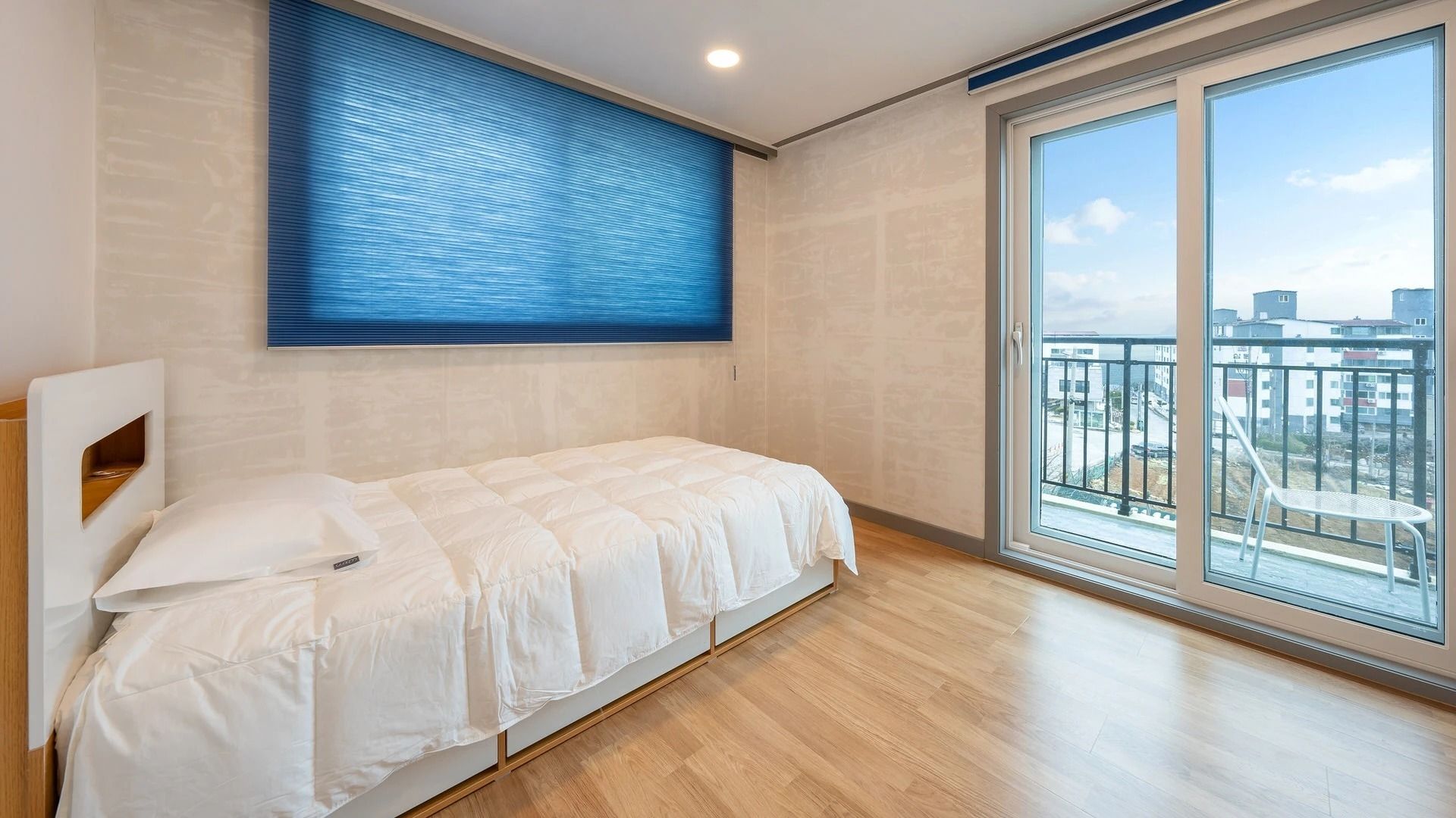 Un dormitorio con una cama, una ventana y vistas a edificios.