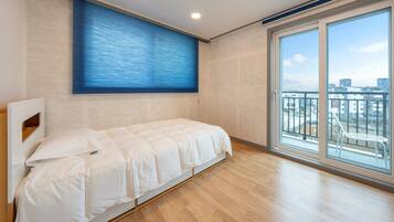 Un dormitorio con una cama, una ventana y vistas a edificios.