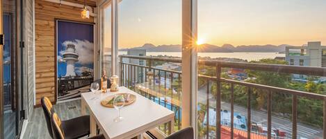 A balcony with a table set for two, a bottle of wine, and a glass.