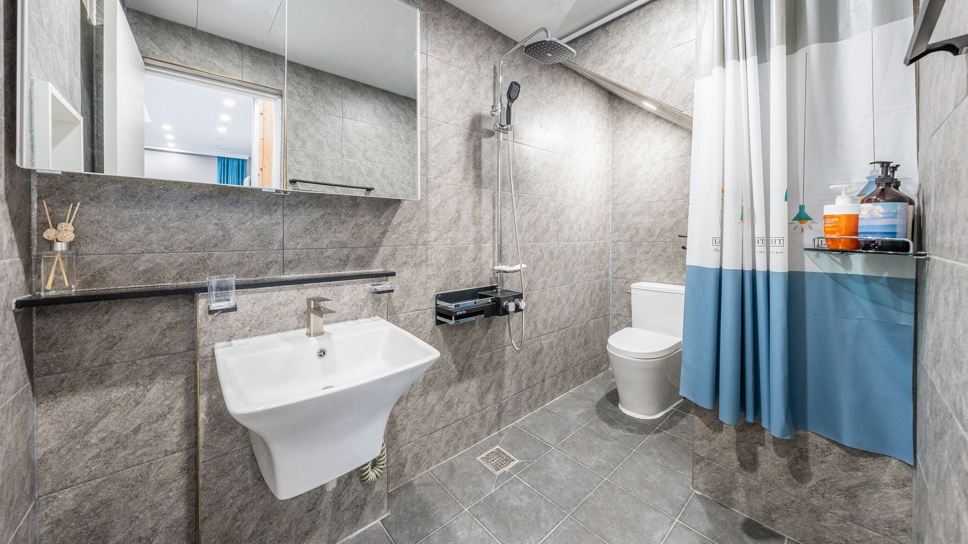 Une salle de bain moderne équipée d’un lavabo, de toilettes, d’une douche et d’un miroir.
