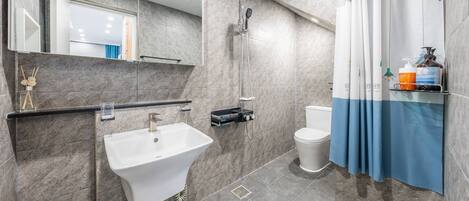 Une salle de bain moderne équipée d’un lavabo, de toilettes, d’une douche et d’un miroir.