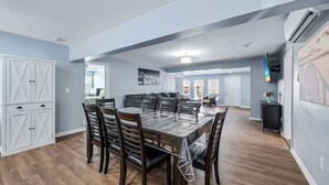 Un coin repas avec une table et des chaises, une cuisine avec des meubles blancs et un salon avec un canapé et un téléviseur.