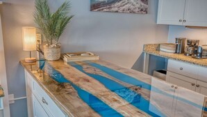 A kitchen with a wooden countertop, a blue water feature, a plant, and a coffee maker. - Oceanfront King Beach Suite- Updated Landmark 1030 (Myrtle Beach)