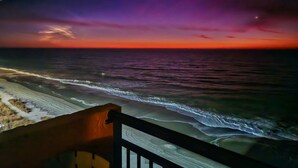 A beach view from a balcony with a railing, ocean waves, and a sunset sky. - Oceanfront King Beach Suite- Updated Landmark 1030 (Myrtle Beach)