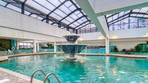 An indoor swimming pool with a central fountain, clear water, and a glass ceiling. - Oceanfront King Beach Suite- Updated Landmark 1030 (Myrtle Beach)