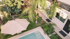 An aerial view of a courtyard with a swimming pool, palm trees, and outdoor seating areas. - Hotel Guitarra Inn (Puerto Escondido)