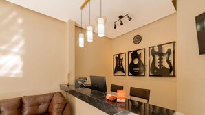 A reception area with a marble counter, a computer, and a chair. There are three wall-mounted guitars and a clock on the wall. - Hotel Guitarra Inn (Puerto Escondido)