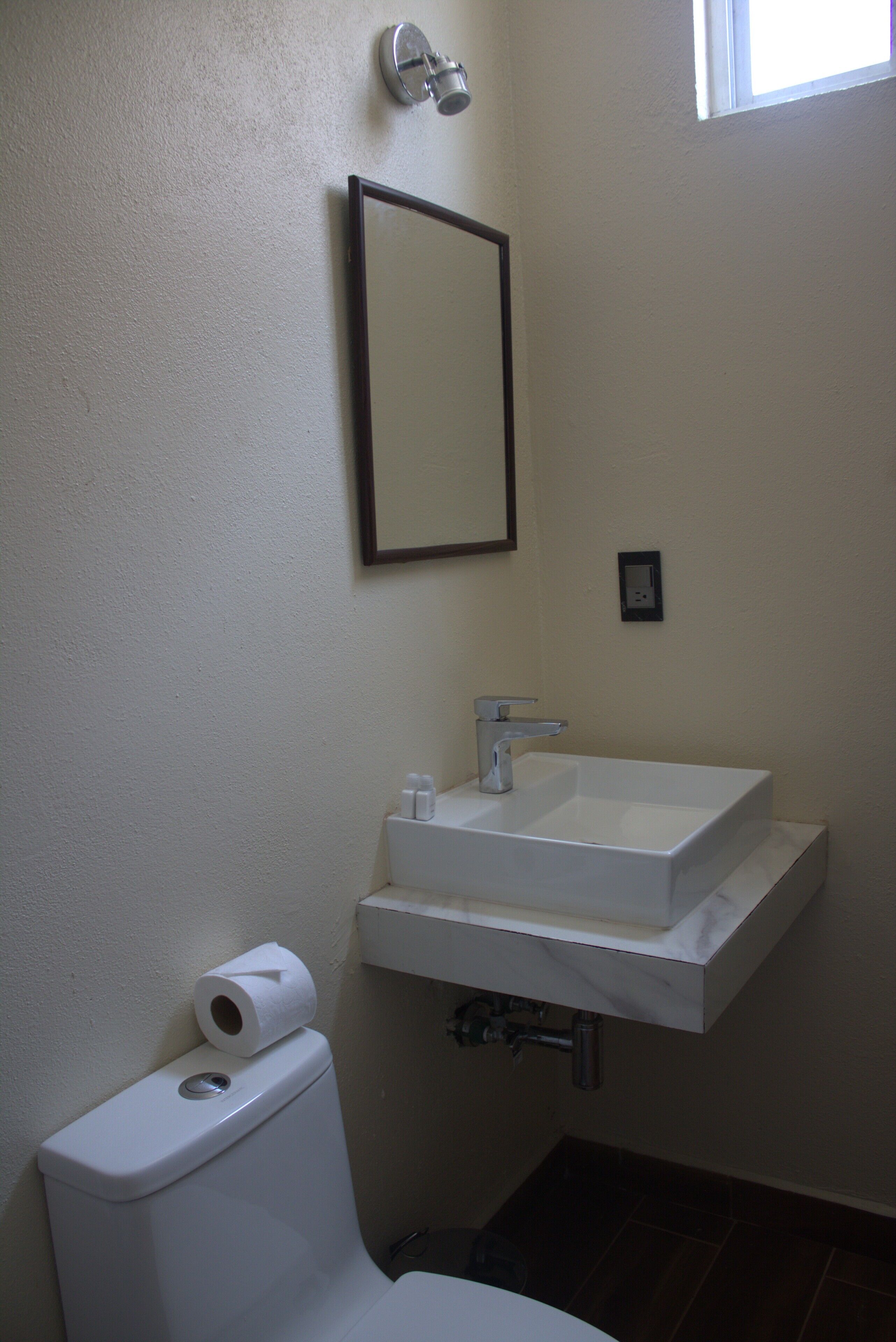 A bathroom with a toilet, a sink, and a mirror.