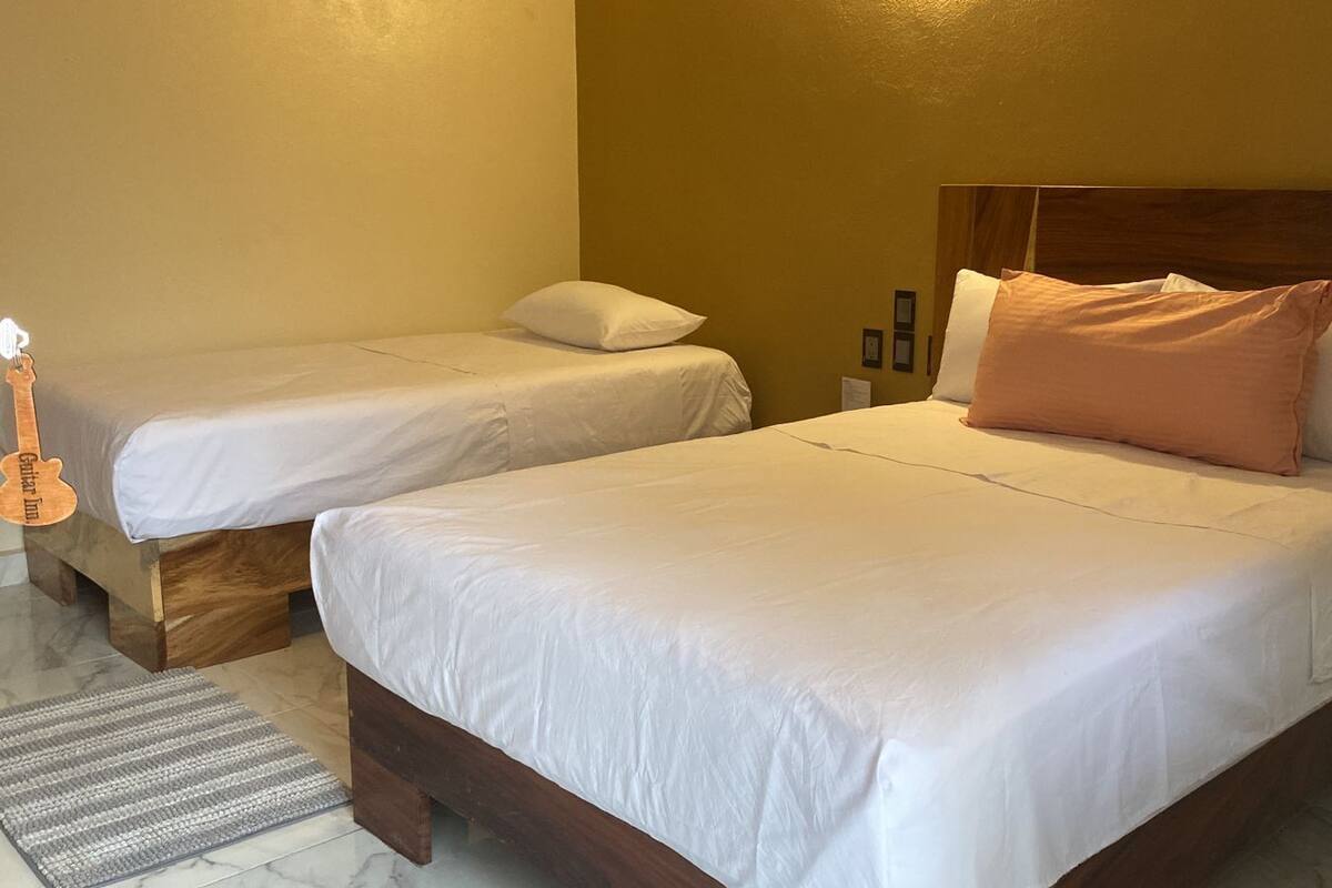 A hotel room with two single beds, a wooden headboard, and a small rug.