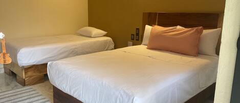 Een hotelkamer met twee enkele bedden, een houten hoofdeinde en een klein vloerkleed.