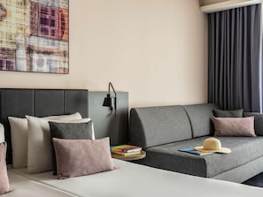 A modern hotel room with a bed, a grey sofa, and a wall-mounted lamp. - Number 11 St Julian's Malta-handwritten Collection (St. Julian's)