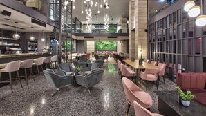 A modern hotel lobby with a bar area, seating arrangements, and a view of greenery through large windows. - Number 11 St Julian's Malta-handwritten Collection (St. Julian's)