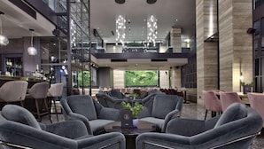A modern interior with grey upholstered chairs, a central table with a vase, and a bar area with stools. - Number 11 St Julian's Malta-handwritten Collection (St. Julian's)