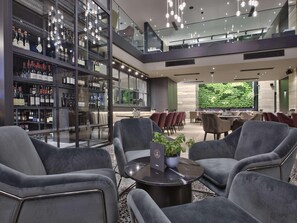 A modern interior with seating, a bar area with wine bottles, and a view of greenery outside. - Number 11 St Julian's Malta-handwritten Collection (St. Julian's)