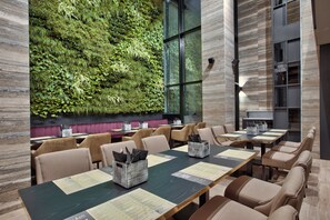 A restaurant with long tables, chairs, and a green wall. - Number 11 St Julian's Malta-handwritten Collection (St. Julian's)