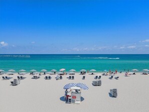 Una platja amb files de gandules i ombrel·les, un servei de socorrises i l'oceà de fons.