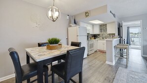 Une cuisine moderne avec des meubles blancs, un pare-feu en pierre et un coin repas comprenant une table et des chaises.