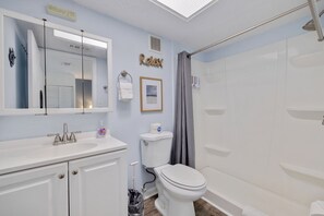 Un baño con lavamanos blanco, espejo, inodoro y ducha.
