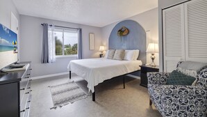 A bedroom with a bed, bedside tables, a sofa, a TV, and a window with curtains.