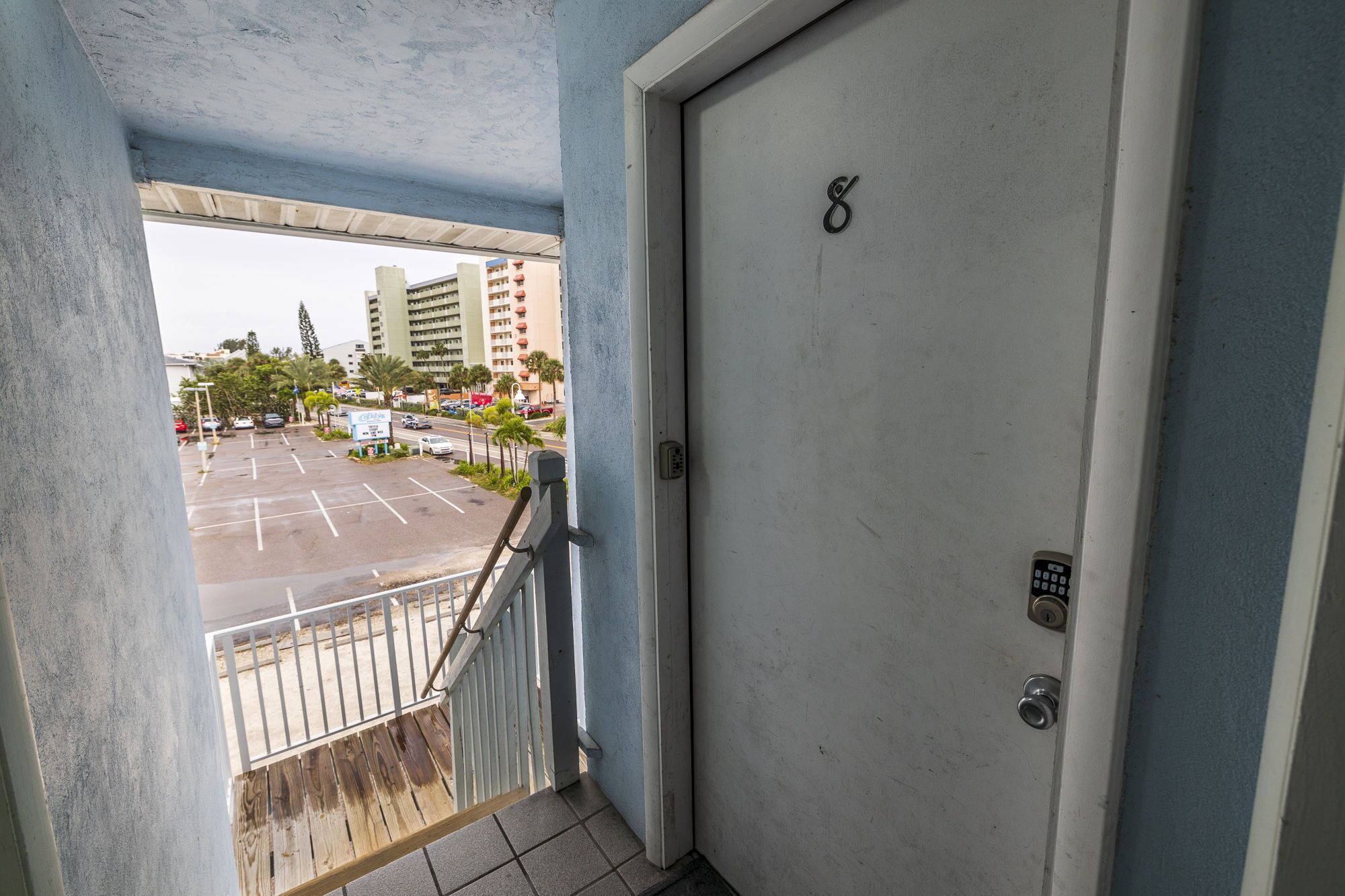 Vista desde un balcón a un estacionamiento con un edificio al fondo.