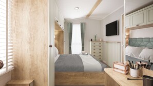 Et soveværelse med seng, kommode, skrivebord med køkkenredskaber og et fjernsyn på væggen.