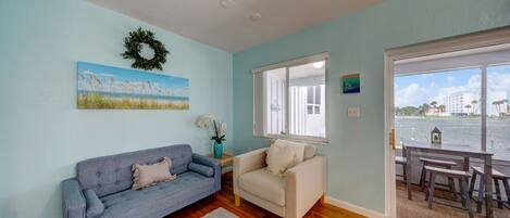 A living room with a blue couch, a beige sofa, and a view of a body of water through a large window.