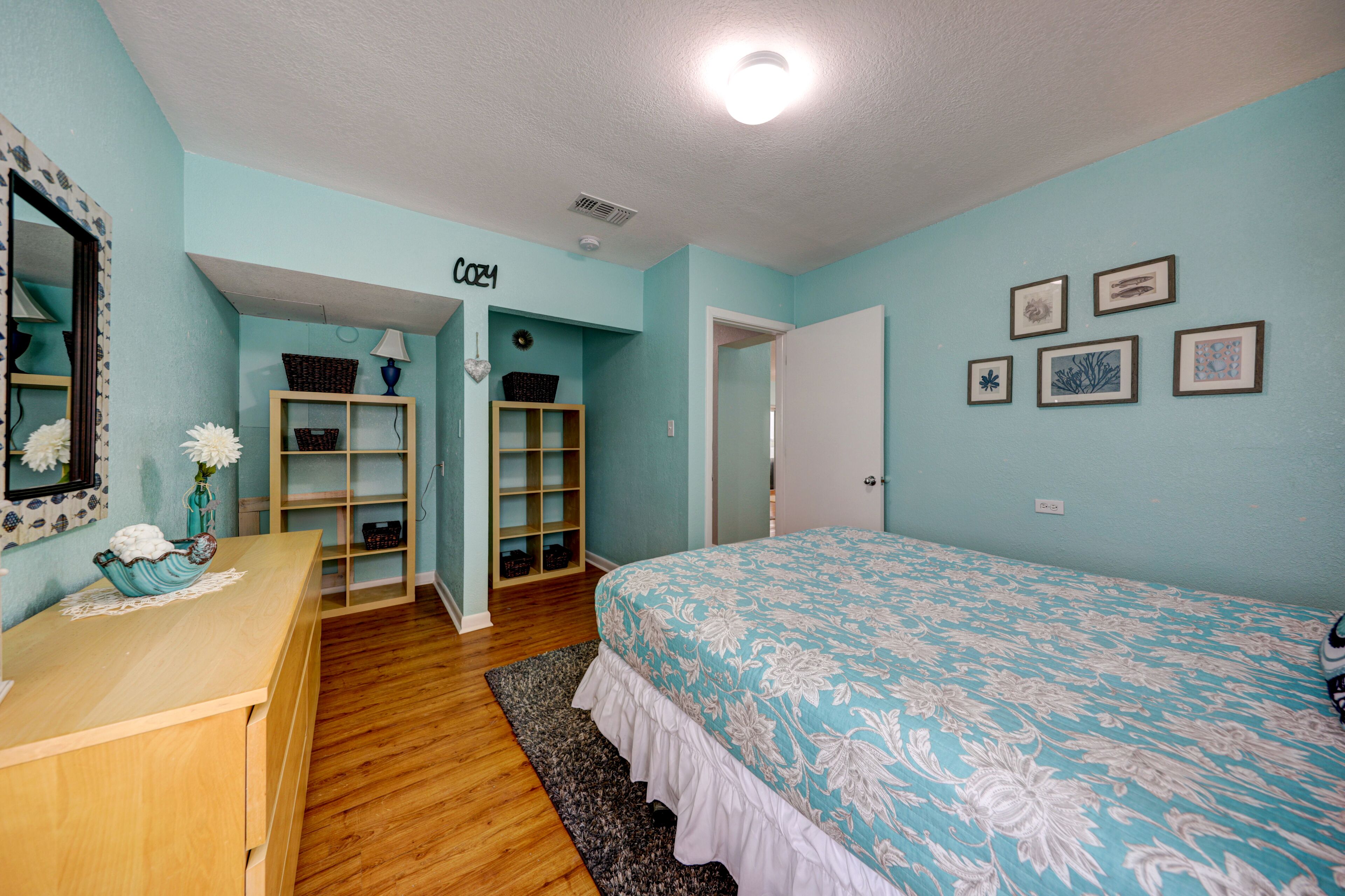 Quarto com cama, penteadeira e estantes.