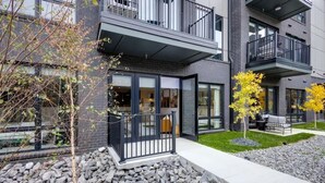A modern multi-story building with balconies, large windows, and a stone pathway. - Tria - 2 Condos - Odyssey (Nashville)